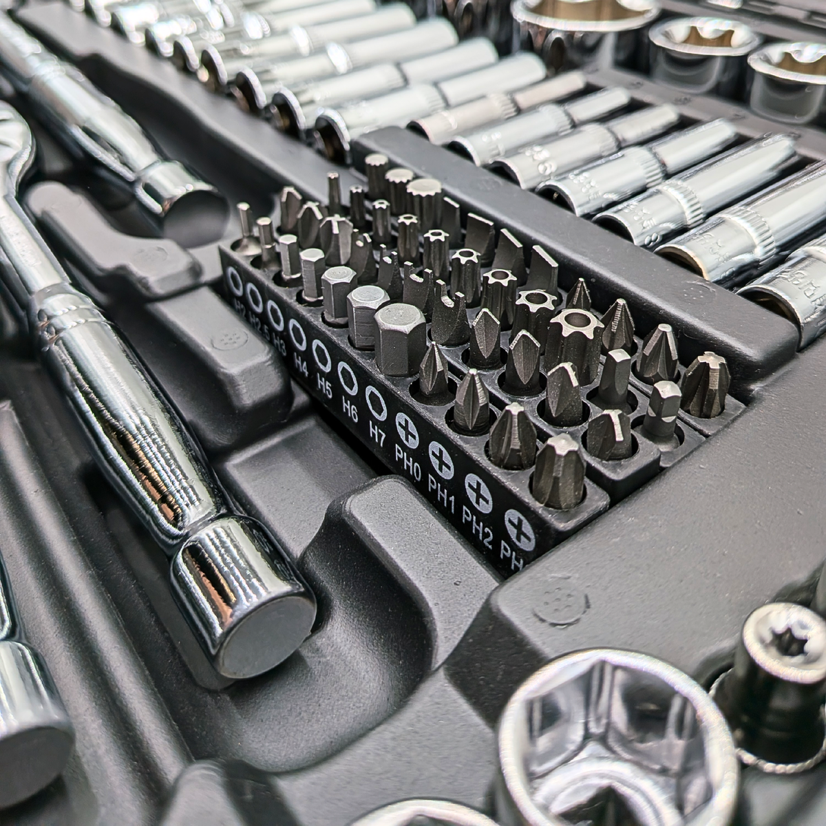 Close-up of screwdriver bits in labelled holders beside sockets in the IRONVOLT 218-piece set.